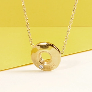 Detail of gold necklace pendant engraved with MY LOVE and set with a sparkling zircon