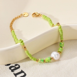 Detailed macro view of green stone beads and a natural pearl on a stainless steel bracelet