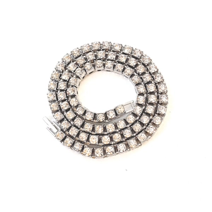 Detail showing a silver tennis chain necklace with clear zircons on a white background