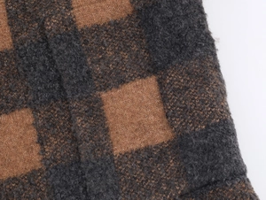 Macro detail of the brown and dark grey checkered knit coat showing soft wool texture