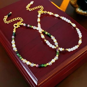 Detail of 18K gold plated beaded bracelets with pearls and stones on a wood jewelry box