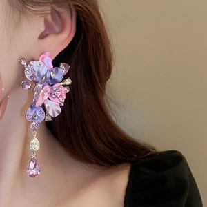 Detail of silver needle earrings with purple floral petals and crystal teardrop pendants
