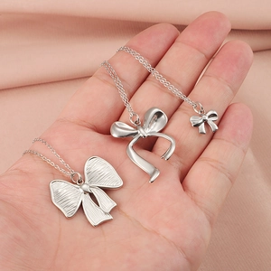 Trois colliers avec pendentif nœud en métal argenté présentés sur un mannequin