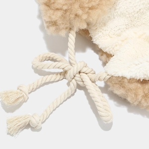 Detail of soft lamb-like plush fabric with cotton drawstring and tassels on a winter hat