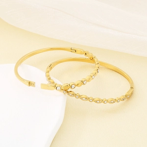 Detailed close-up of 18K gold plated oval bangles featuring white zircon and wavy metal texture
