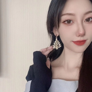 Golden hollow Christmas tree earrings with star stud shown worn on model for holiday style