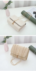 Detail view of a beige woven crossbody bag featuring golden hardware and chain strap