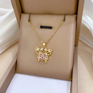 Macro view of gold butterfly pendant with pink stone and white diamonds on chain