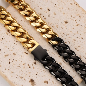 Chunky gold and black two-tone stainless steel Cuban chain necklace on stone base