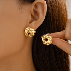 Detailed close-up showing the size and metallic luster of gold knot stud earrings on ear
