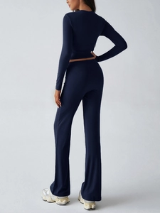 Rear view of women's navy blue yoga set featuring a tight long sleeve top and flared pants