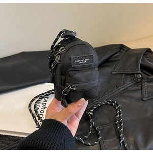 Close-up of mini black nylon shoulder bag featuring dual zippers and adjustable woven strap