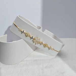 Detail of adjustable gold-tone bracelet with white cat-eye clover flower and zircon stones
