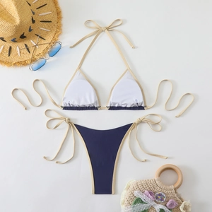Flat lay of navy blue halter bikini set with white straps and beach accessories