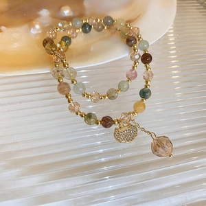 Macro detail of layered crystal lily of the valley bracelet with a golden ruyi lock pendant
