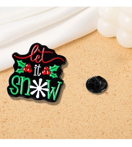 Macro detail of 'Let it Snow' Christmas enamel pin with holly berry design and rubber back