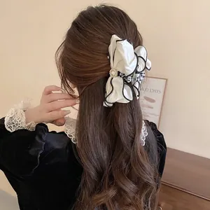 Elegant white chiffon bow hair claw with pearl detail on woman from a back view