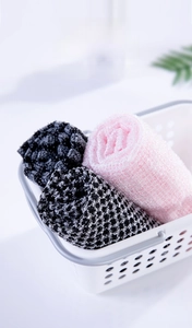 Close-up of pink and checkered exfoliating washcloths in a white bathroom basket