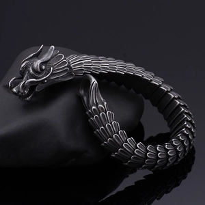 Macro shot of silver dragon scale steel bracelet wrapped on a black stone with reflections