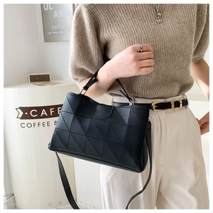 Detail of black geometric quilted handbag with adjustable strap in a modern cafe setting