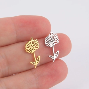 Minimalist 18k gold and silver flower pendants held between fingers for scale