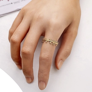 Macro view of adjustable golden vine leaf ring made of titanium steel on finger
