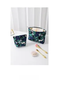 Detail of vintage floral jacquard fabric and brand tag on a premium blue cosmetic bag