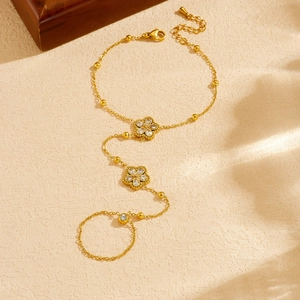 Elegant gold flower bracelet with crystal accents and chain tassel on textured background