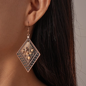 Close-up of vintage bronze hollow diamond earrings with coconut beads on a model