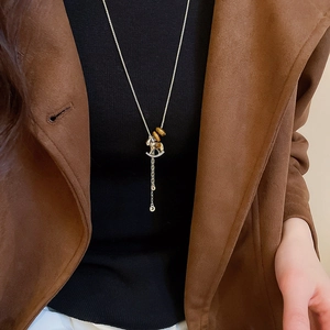 Long golden sweater necklace with tiger eye beads and horse pendant on a black sweater