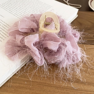 Vue détaillée d'une pince à cheveux lavande avec fleurs en tissu et pompons soyeux