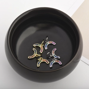Macro view of tiny rainbow zirconia pendants in gold and silver plating inside a black bowl