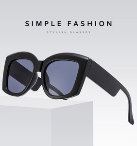 Detail view of stylish thick black frame sunglasses with dark lenses on a pedestal