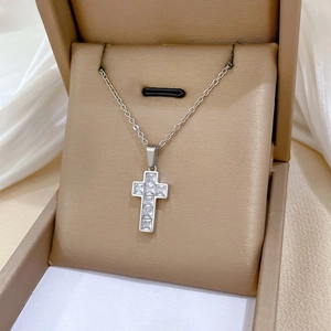 Detailed view of silver cross pendant with sparkling zircons on elegant silk fabric