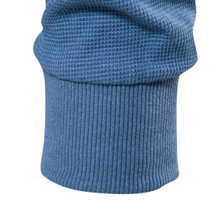 Vue détaillée du tissu gaufré bleu marine et des poignets côtelés sur ce haut henley