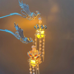 Elegant silver phoenix hair pin with glowing lantern and pearl tassels on brown background