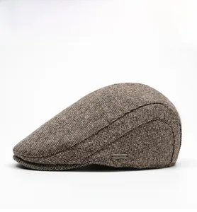 Detailed side view of brown tweed flat cap showing textured knit and metal logo plate