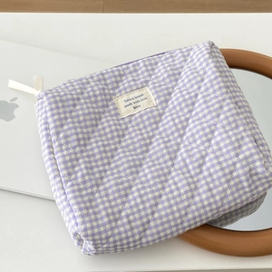 Detailed macro of berry checkered quilted makeup bag with zipper and woven fabric label