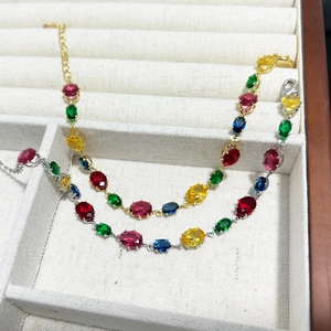 Detail of colorful oval-cut gemstone bracelets in gold and silver settings on velvet