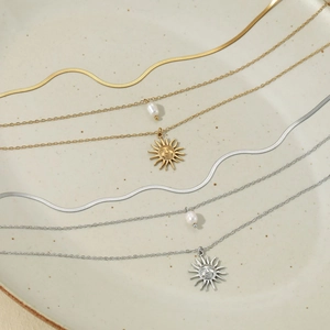 Detailed view of layered sun pendant and pearl necklaces in gold and silver finishes