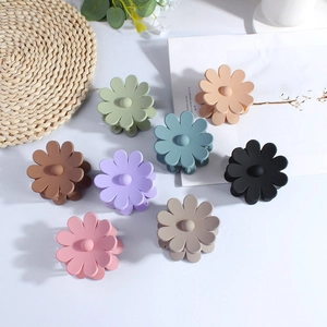 Top view of eight matte flower hair claws in assorted pastel colors on a white desk