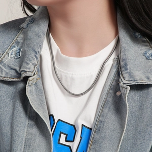Close-up of polished silver snake bone chain necklace worn on a model with denim jacket
