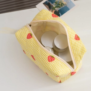 Quilted yellow gingham makeup bag with strawberry print and white cosmetic containers