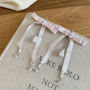 Close-up of pink polka dot bow earrings with pearls and crystals on a book