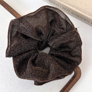 Detail view of shimmering grey double-layer lace scrunchie on a rustic wooden tray