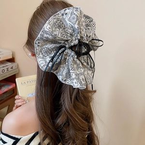 Macro shot of paisley print bow hair claw with pearl details on long wavy hair