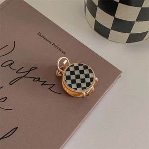Macro view of checkered round hair claw clip with golden alloy base on a vintage book
