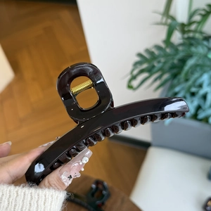 Detail of dark brown glossy hair claw clip with strong golden metal spring mechanism