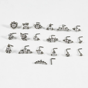 Macro view of G23 titanium nose studs with zircon stones arranged on a white background