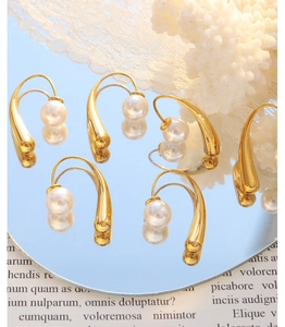 French vintage earrings with curved gold metal bars and elegant white pearls on mirror